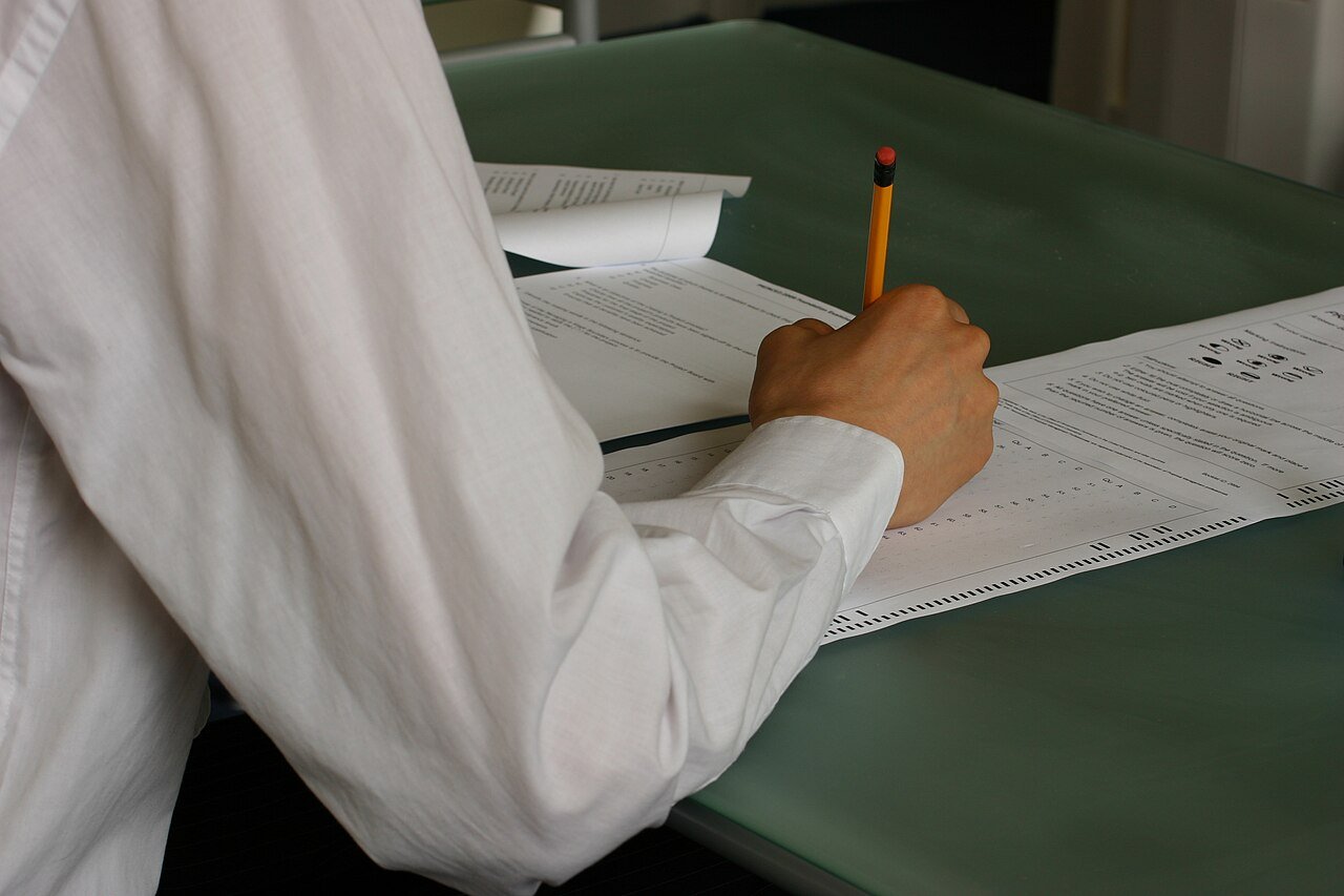 Candidate rédigeant sa copie à la main dans une salle d'examen